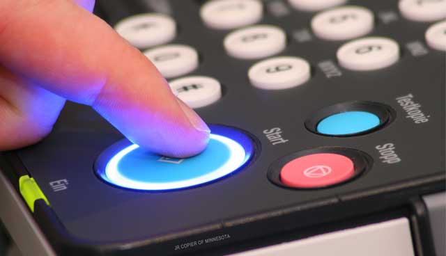 Finger pressing the Start button on a rental copier control panel